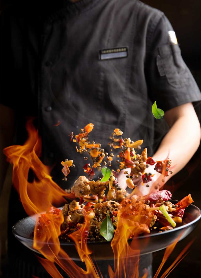 A Neptune chef tossing a flaming wok of seafood and chilies